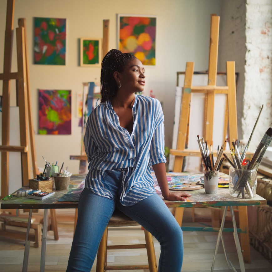 From Image 3. Prompt: “An artist in her studio sitting at desk looking pensive with tons of paintings and ethereal.” Image Credits: Adobe